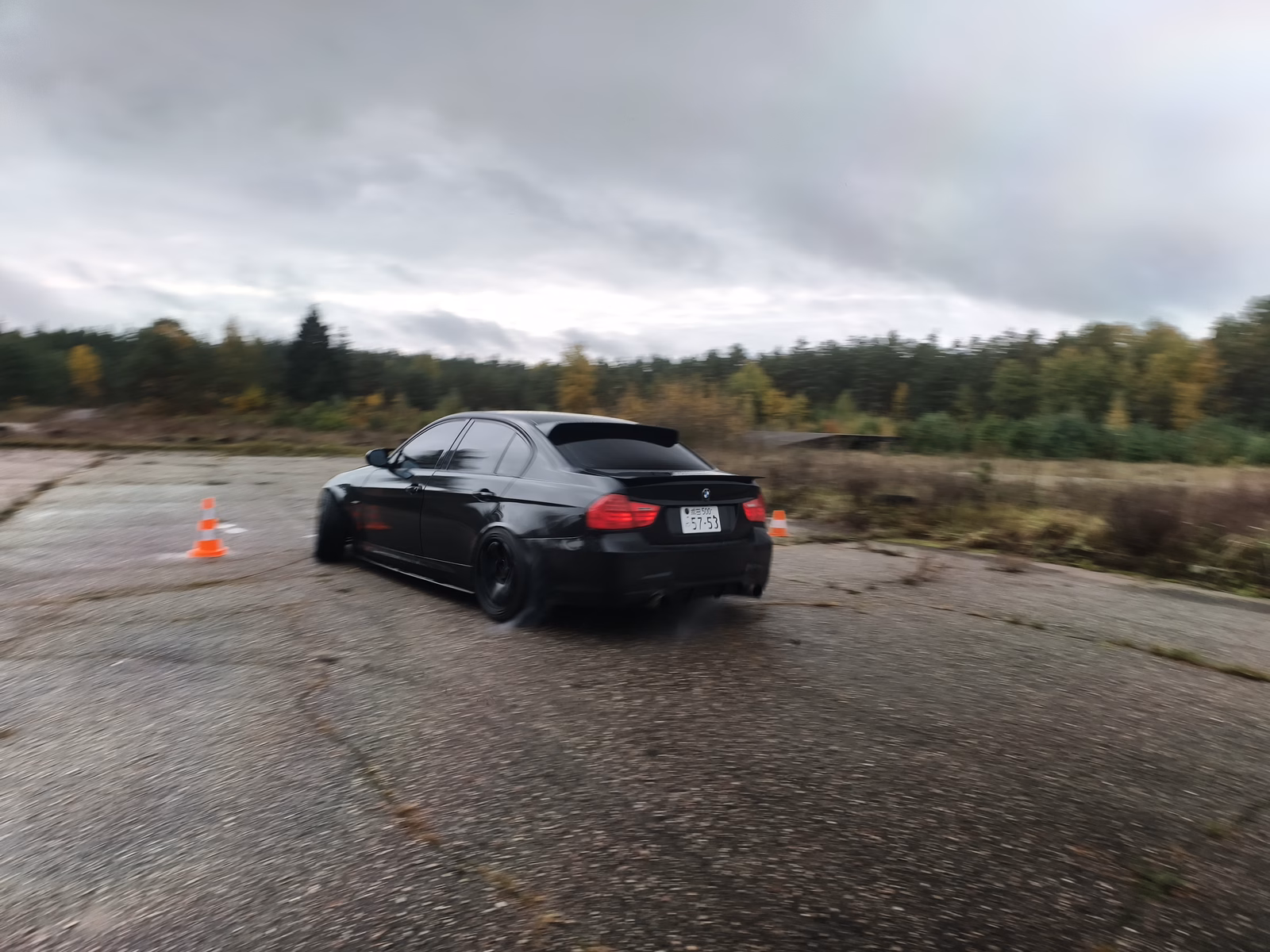 Automobilis asfaltuotoje aikštelėje su oranžiniais kūgiais.